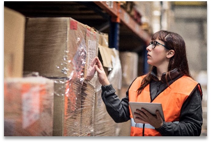 Woman wearing orange vest working in warehouse